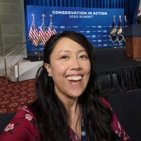 Kim in front of a stage with a blue curtain